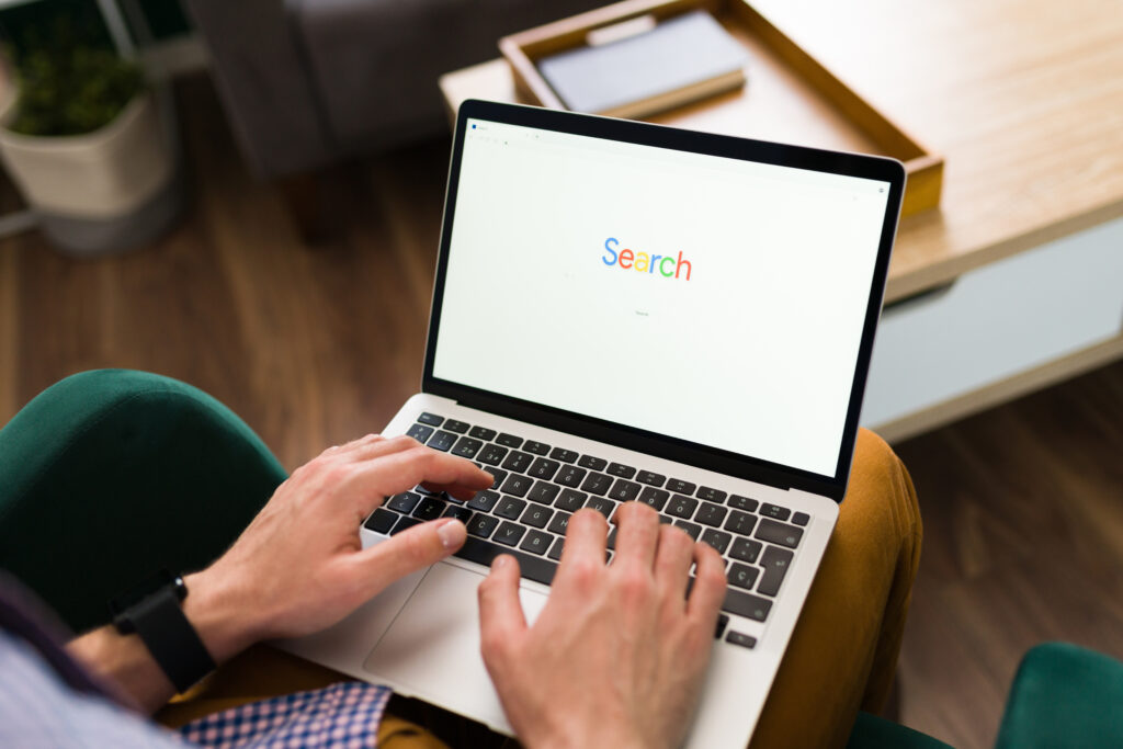 Person typing on a laptop with Google search on the screen for SEO by Elevation Marketing