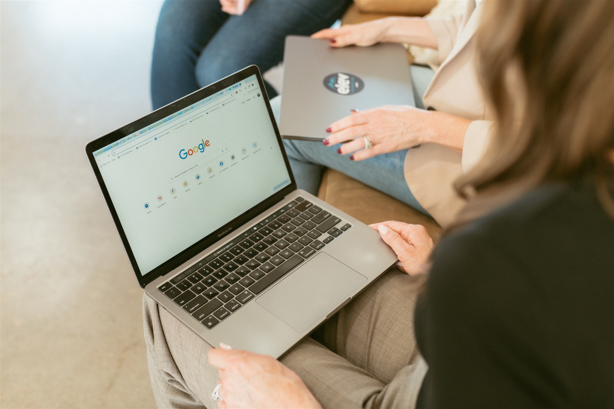 Danielle Joyce, Amanda Joyce and Devon Hayes, contracting marketing experts at Elevation Marketing holding a laptop collaborating for SEO services.