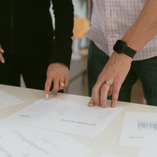 Two team members analyze printed lead generation performance reports for roofing contractors, highlighting Elevation Marketing’s data-driven strategy to improve client results