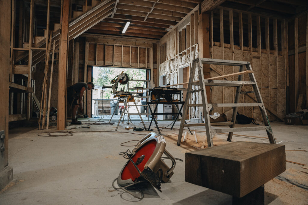 Inside of a construction project in progress with framed walls and saw with saw horse for cutting wood