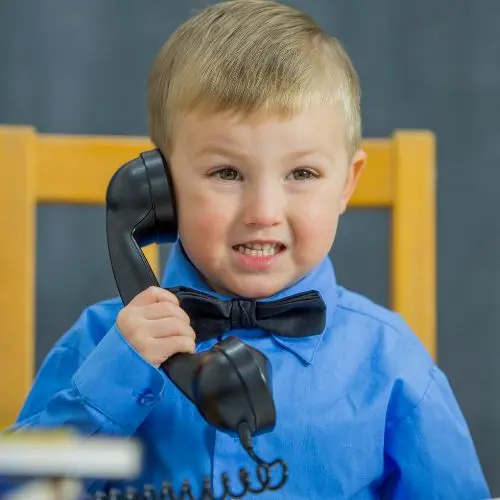 Young boy in blue shirt talking on telephone, demonstrating the concept of reaching customers with local Google ads by Elevation Marketing