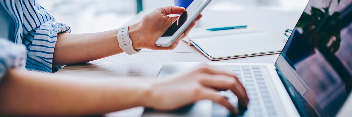 Hands using smartphone and laptop to research what is entity SEO and entity SEO concepts by Elevation Marketing
