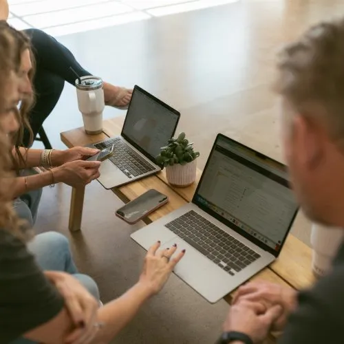 Business professionals reviewing client testimonials on laptops during a marketing strategy session by Elevation Marketing™ | Contractor Marketing Agency