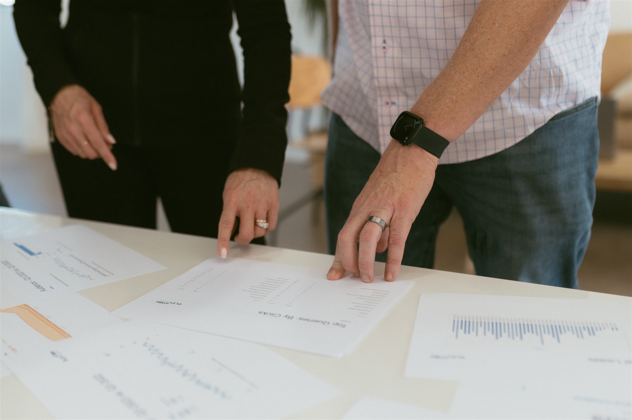 Two team members examining printed performance reports on a table to optimize fractional CMO for contractors fractional CMO services in Denver by Elevation Marketing